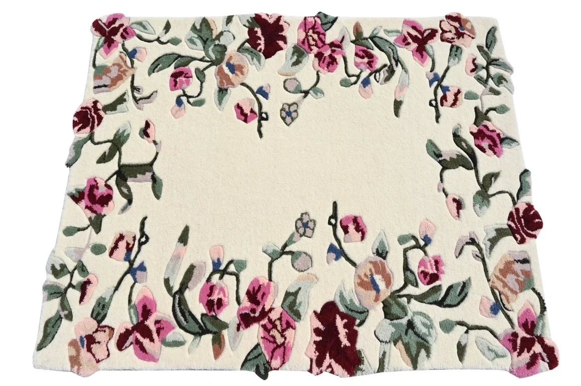 A square cream-colored area rug with a dense floral border pattern featuring pink, burgundy, and green flowers with small blue accents.