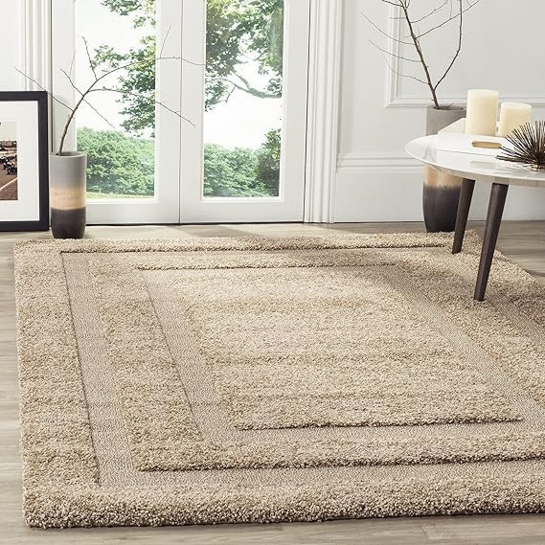 Beige area rug in a room with large windows and a table with candles.