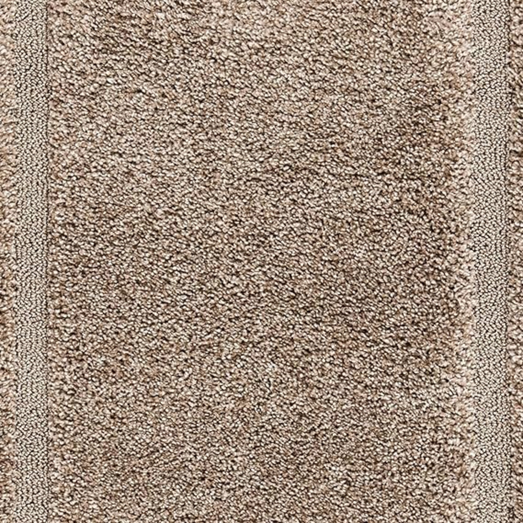 Close-up of a shaggy area rug in a warm taupe-brown color, showing the high-pile texture and a subtle woven border.