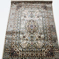 A traditional oriental-style area rug with an intricate floral and geometric pattern, featuring a central medallion, detailed borders, and cream-colored fringe on the top and bottom edges.