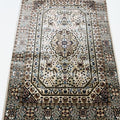 A traditional oriental-style area rug with an intricate floral and geometric pattern, featuring a central medallion, detailed borders, and cream-colored fringe on the top and bottom edges.