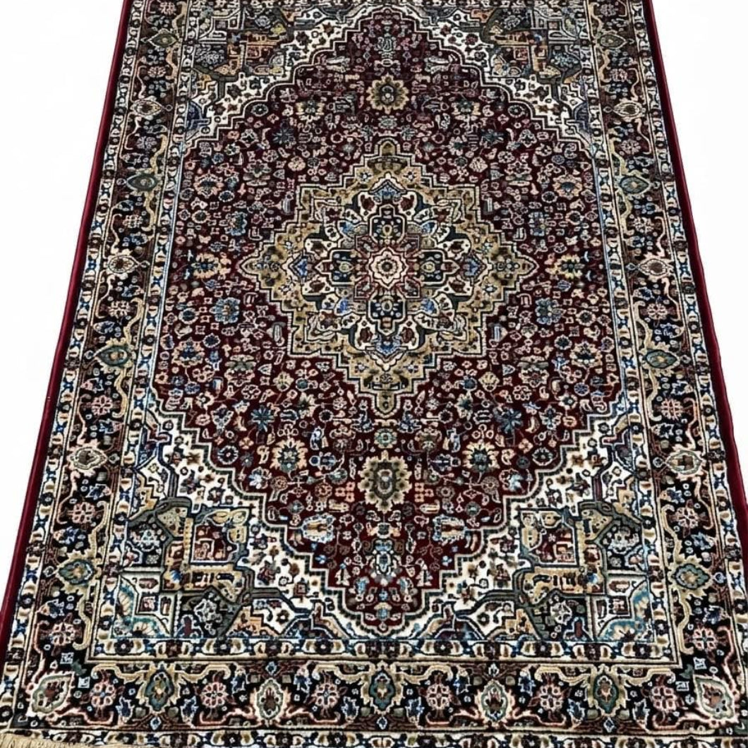 A traditional oriental area rug with an intricate floral and geometric pattern, featuring a dark red central field, beige and blue borders, and cream-colored fringe on the top and bottom edges.