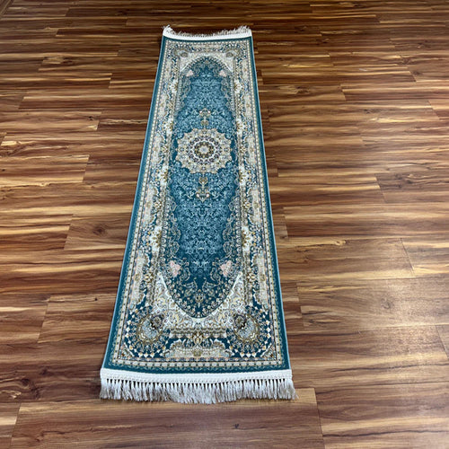 A long rectangular area rug with an ornate traditional pattern in teal blue, cream, and beige, laid out on a polished brown wooden floor.