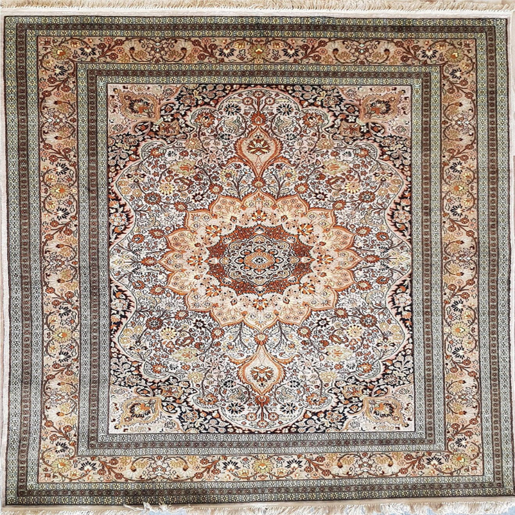 A square traditional area rug with an intricate floral and medallion pattern, featuring a central floral motif and a wide decorative border. The color palette is a warm mix of beige, brown, rust red, and muted blue, finished with white fringe on the top and bottom edges.