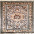 A square traditional area rug with an intricate floral and medallion pattern, featuring a central floral motif and a wide decorative border. The color palette is a warm mix of beige, brown, rust red, and muted blue, finished with white fringe on the top and bottom edges.