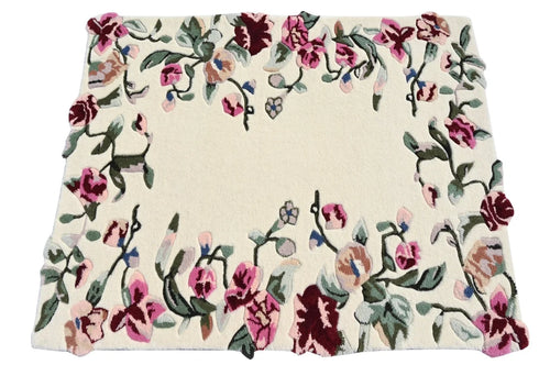 A square cream-colored area rug with a dense floral border pattern featuring pink, burgundy, and green flowers with small blue accents.