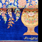 A close-up of a richly patterned rug featuring a large ornate golden vase with floral motifs on a deep blue background, with additional floral vine patterns and Persian script near the bottom.